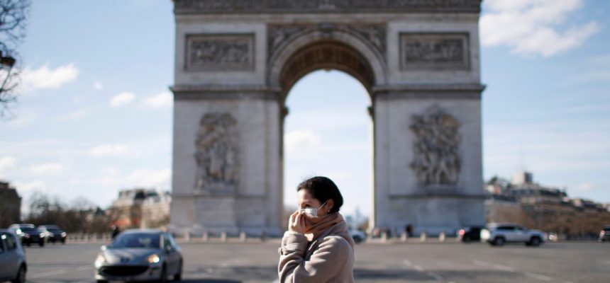 Uma mulher usando uma máscara protetora caminha perto do Arco do Triunfo enquanto a França enfrenta um surto de doença por coronavírus (COVID-19), em Paris