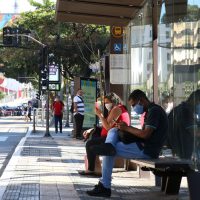 Usuários de transporte público usam máscaras de proteção contra covid-19 em ponto de ônibus na rua da Consolação